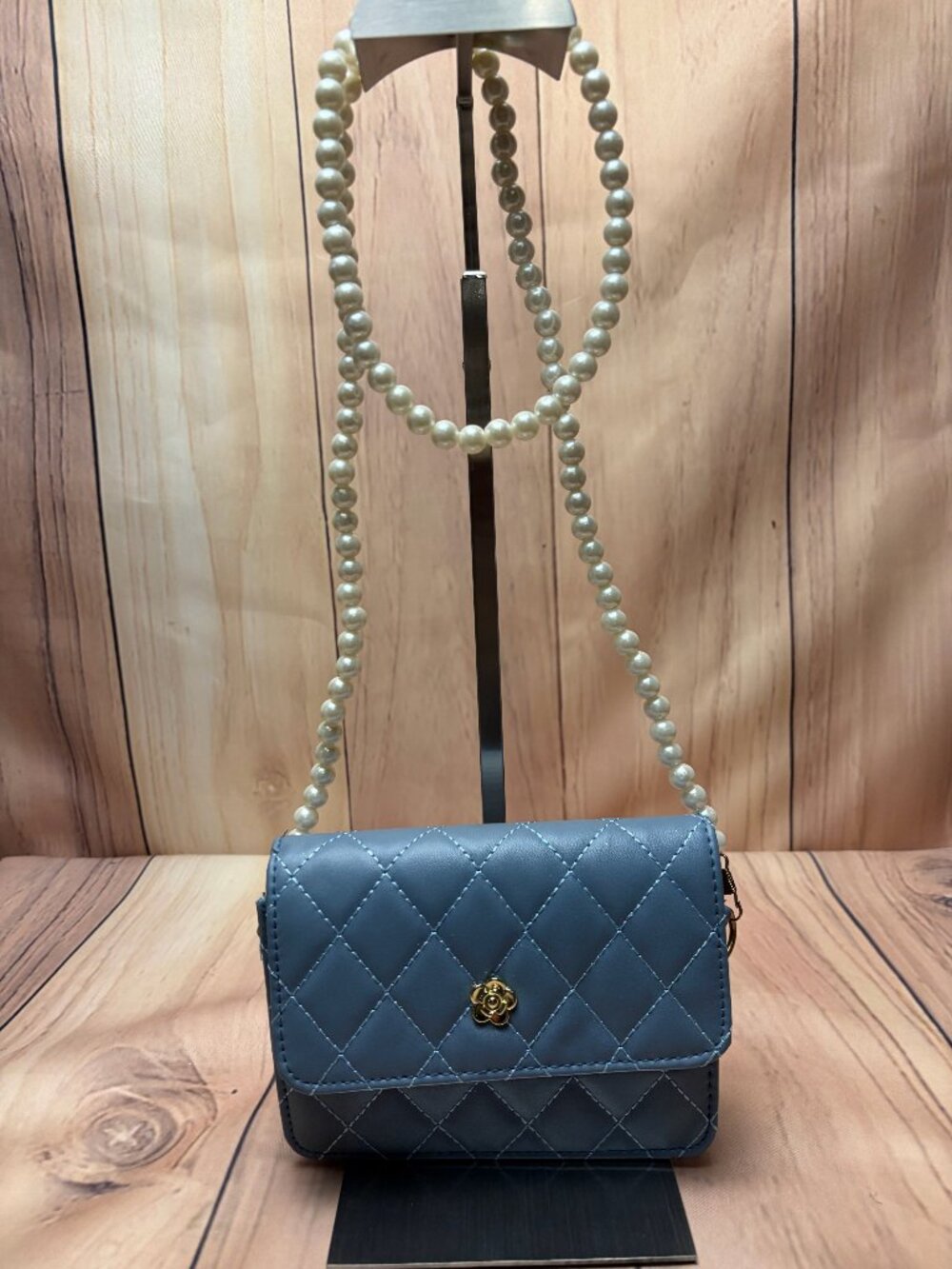 Light blue quilted mini crossbody bag features a distinctive faux pearl strap